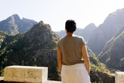 Rear view of man looking at mountains against sky