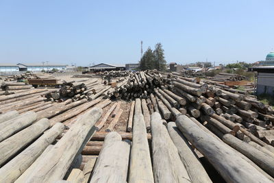 Stack of wooden logs against clear sky