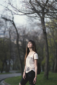 Woman standing against bare trees at park