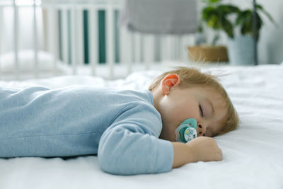 Close-up of cute baby boy sleeping on bed at home