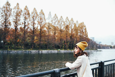 Woman looking away by lake against sky