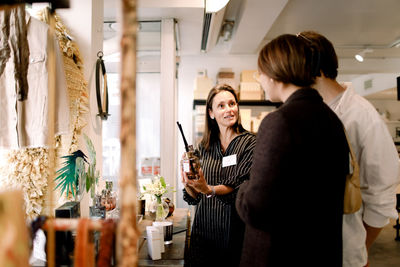 Saleswoman showing perfume to couple at fashion store