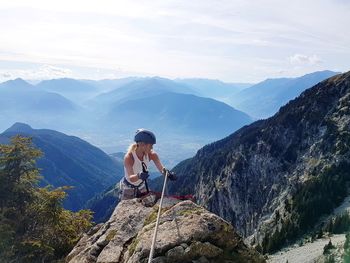 Woman climbing on rock against mountains with sweety equipment