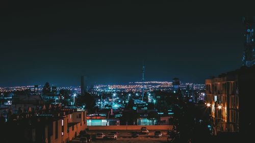 Illuminated cityscape against sky at night