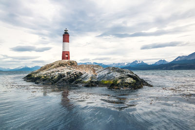 Lighthouse by sea against sky