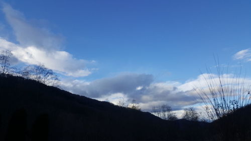 Low angle view of silhouette mountain against blue sky