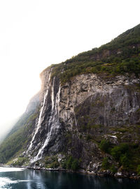 Rock formations by sea against clear sky