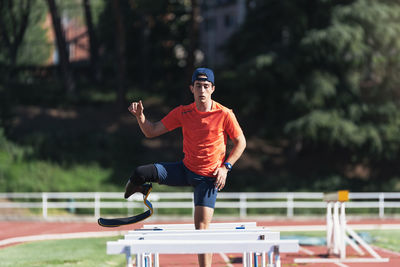Young athlete with prosthetic leg standing amidst railings on running track