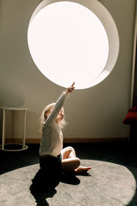 Girl gesturing while sitting on floor in hotel room