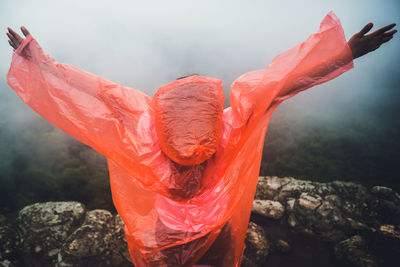 Rear view of woman with arms outstretched during rainy season