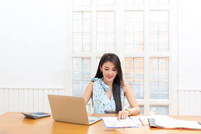 Young woman using phone while sitting on table
