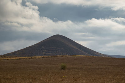 Scenic view of desert against cloudy sky