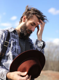 Man with head in hand against sky