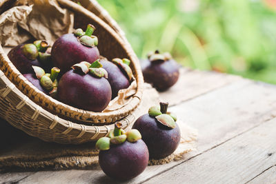 Close-up of purple mangosteens in basket on table