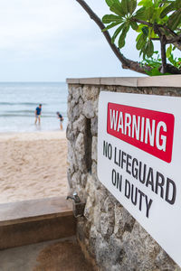 Information sign on beach against sky