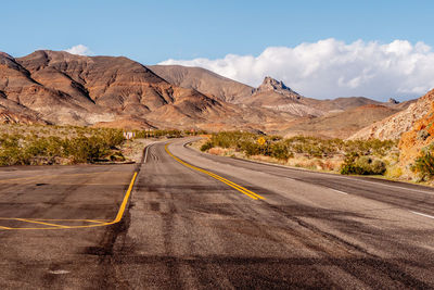 Empty road by desert against sky