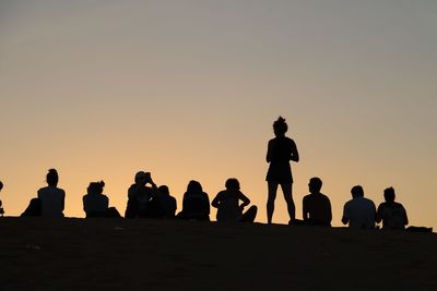 Silhouette people against clear sky during sunset