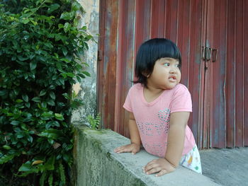 Cute girl looking away while sitting outdoors