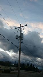 Low angle view of electricity pylon against cloudy sky