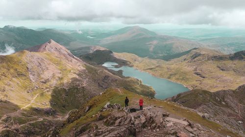 Scenic view of mountains with people on rock against sky