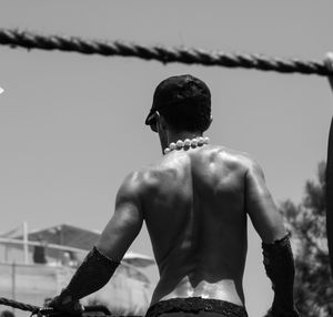 Rear view of shirtless man against sky
