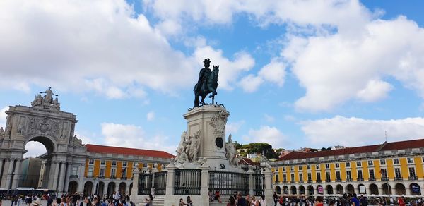 Statue in front of historical building against cloudy sky