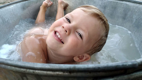 Smiling boy in the bathtub with foam
