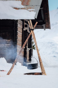 Snow covered chalet and campfire with hot pot in winter