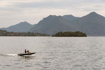 Man rowing boat in lake against mountains