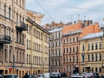 Cars on road by buildings in city against sky