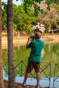 Rear view of man photographing lake