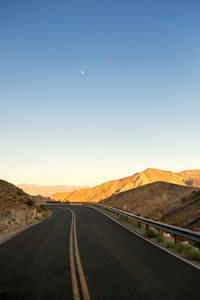 Road amidst mountains against clear sky