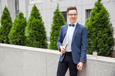 Portrait of young man standing against plants