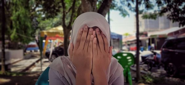 Portrait of person hiding behind covered with city in background