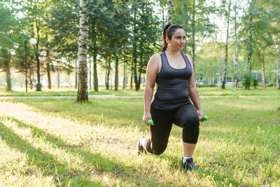 A charming brunette woman plus-size body positive practices sports in nature. 