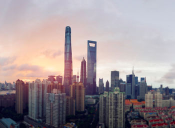 Modern buildings in city against sky during sunset
