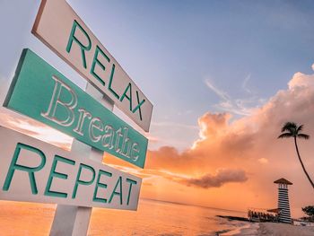 Low angle view of information sign against sky during sunset