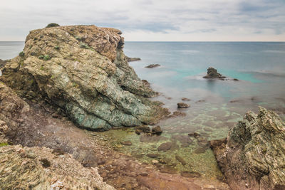 Rock formation in sea against sky