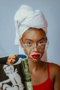 Portrait of young woman reading a magazine blue background