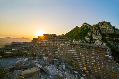 View of broken brick wall by mountain during sunrise