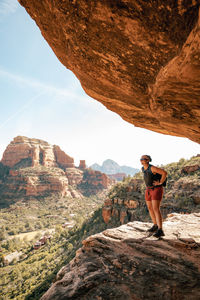 30s female stands on cliff enjoying views of boynton canyon in sedona.