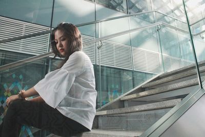 Young woman sitting on steps in building