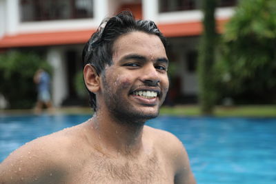 Portrait of shirtless smiling young man in swimming pool