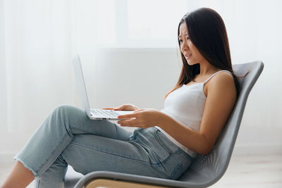 Young woman using laptop while sitting on sofa at home