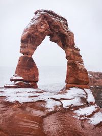 Rock formation in sea against clear sky