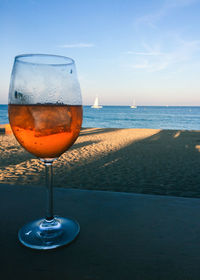 Wineglass on table by sea against sky