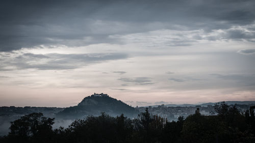 Silhouette of trees against cloudy sky