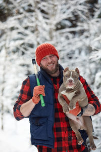 Portrait of smiling young man with dog on snow