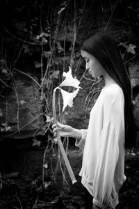 Asian teenage girl in purple blouse holding white flowers in her hands vi