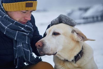 Close-up of man with dog sitting outdoors during winter